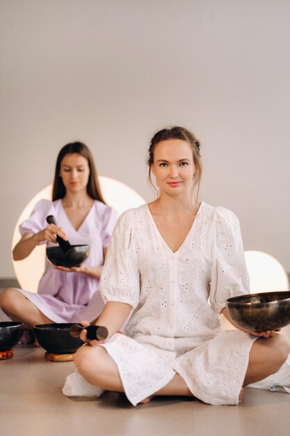 Two female yoga teachers playing a Tibetan bowl in the gym during a yoga retreat