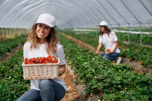 Two females are posing with basket of strawberries