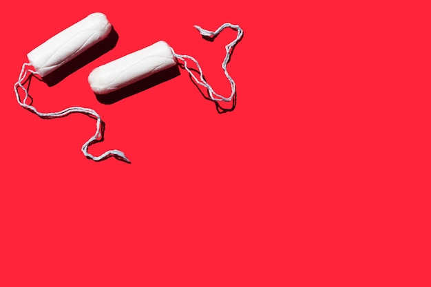 two feminine hygiene tampons on a red background Menstruation concept