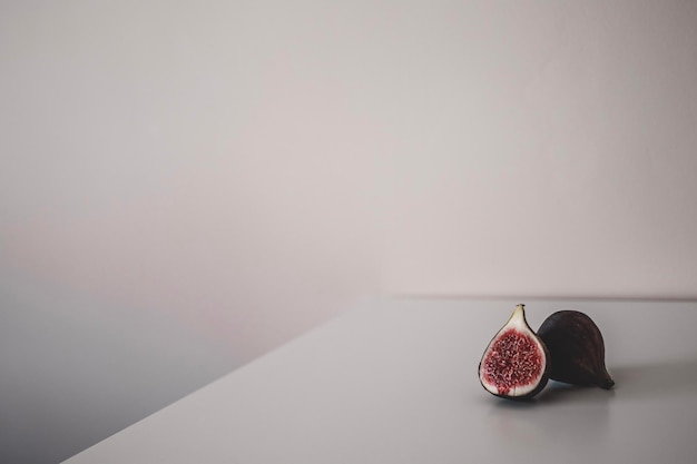Two figs are lying on the table on grey background Minimalism decor One fig in a cut