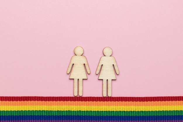 Photo two figures of girls on a ribbon in lgbt colors. flat lay.