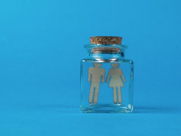 Two figures of a man and a woman in a glass tube on a blue background. The concept of artificial insemination.