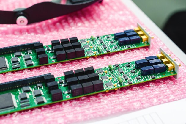 The two finished electronic boards lie on a pink polyethylene substrate