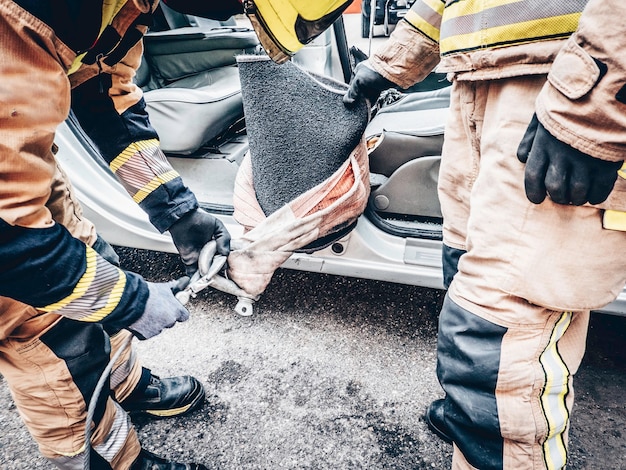 Two firefighters place hooks with slings in traffic accident