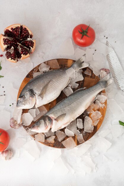 Two fish on a plate with ice and tomatoes on the table