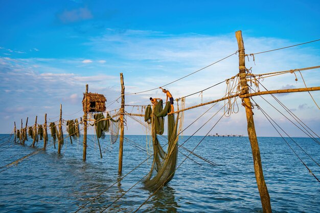 美しい日の出に釣り竿に網を投げる2人の漁師伝統的な漁師が漁網を準備し、地元の人々はそれを日ハングコイと呼ぶ漁業と日常生活のコンセプト