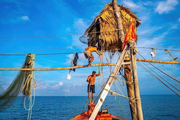 Два рыбака забрасывают сети на удочки на прекрасном восходе солнца Традиционные рыбаки готовят рыболовную сеть, местные жители называют это днем ханг хой Концепция рыболовства и повседневной жизни