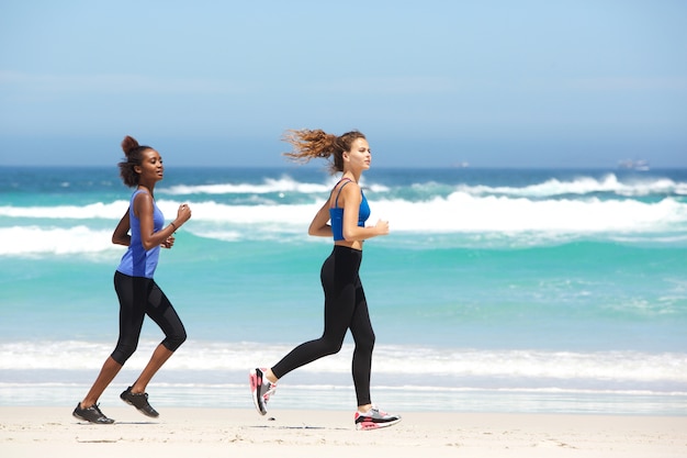 Two fit young women running along the beach