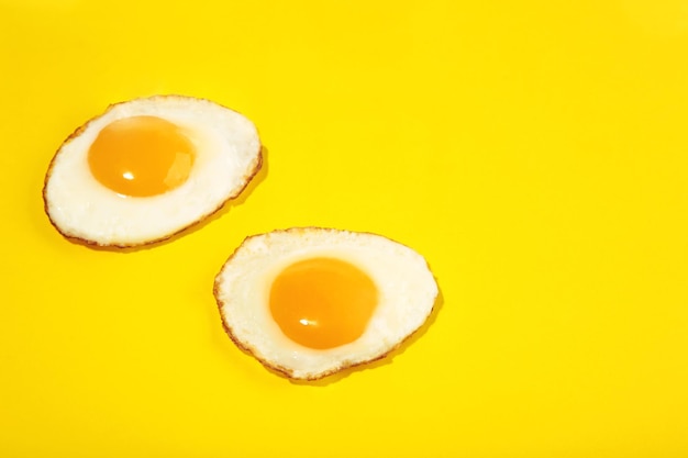 Два безупречных жареных яйца на желтом фоне.