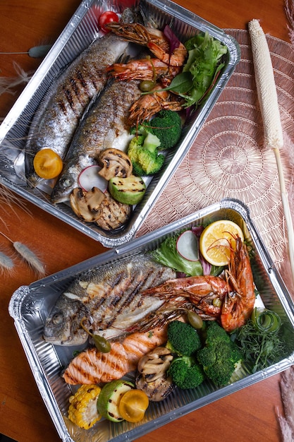 Two foil packages with fried fish steaks and shrimp