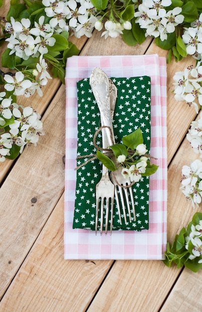 Two forks on rustic wooden surface and branches with flowers