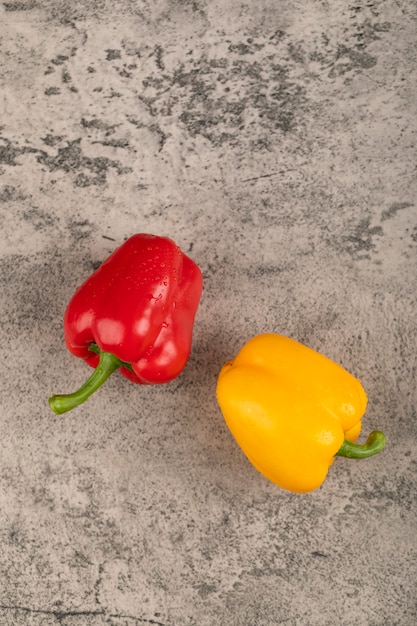 Two fresh bell peppers placed on stone surface