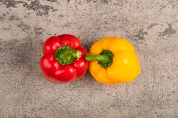 Two fresh bell peppers placed on stone surface