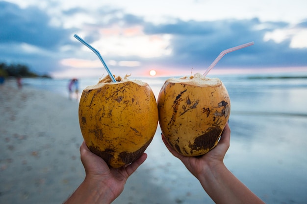 Two fresh coconut cocktail with cocktail straw in his hands