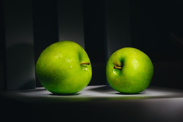 Two fresh green apples on a dark background