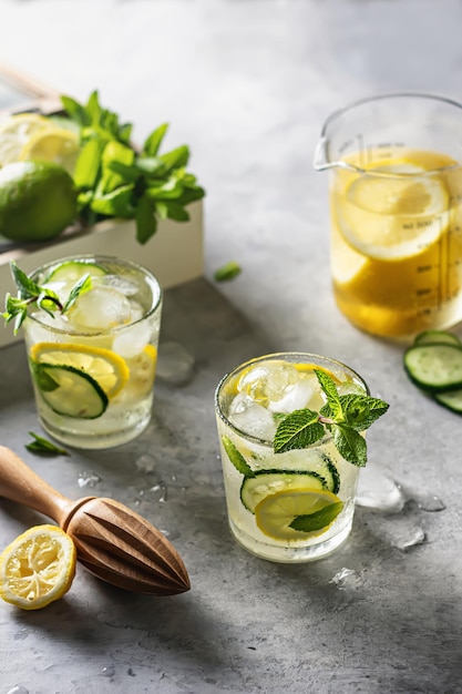Two fresh ice lemonades with lemon and cucumber on a gray background