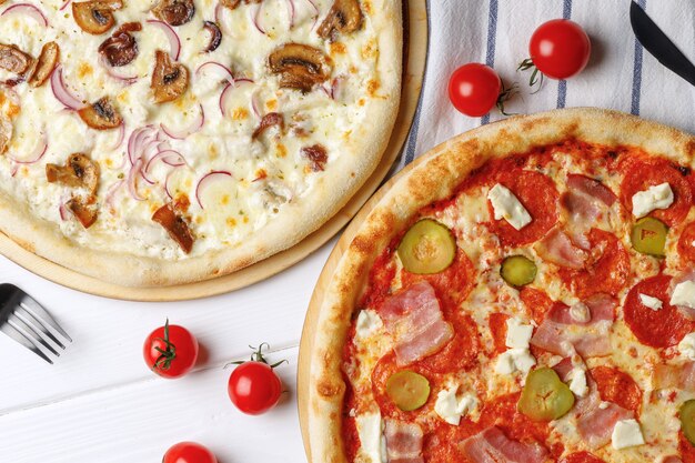 Two fresh pizzas on white wooden table close up photo