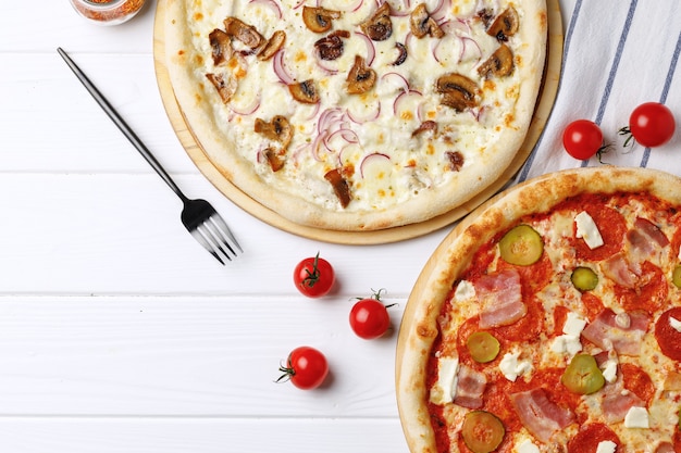 Two fresh pizzas on white wooden table