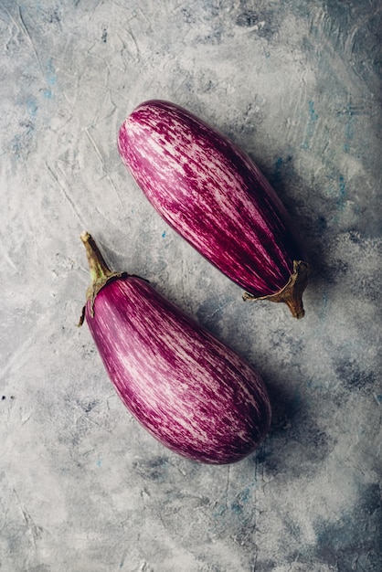 Two fresh purple eggplants on light concrete background