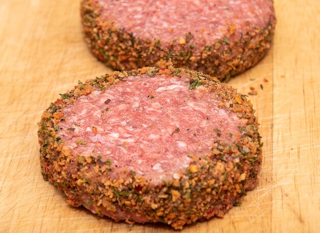 Photo two fresh raw lamb burgers on wooden chopping board.