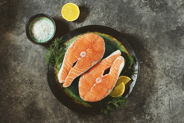 Two fresh raw salmon steaks on a gray concrete background