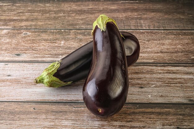 Two Fresh ripe black eggplants over wooden background for cooking