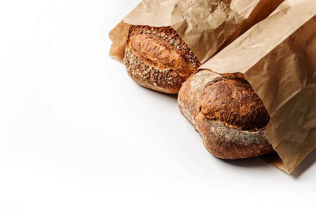 Two fresh rustic breads in craft bags