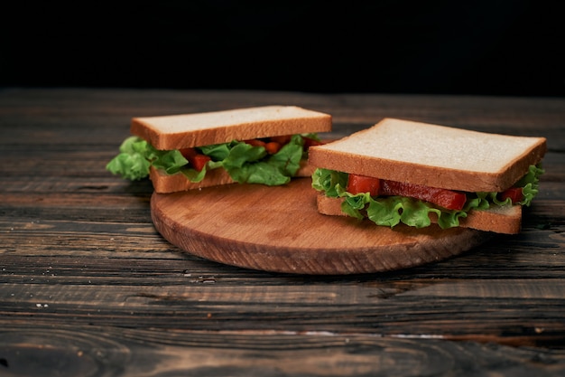 Two fresh tomato sandwiches on a wooden board