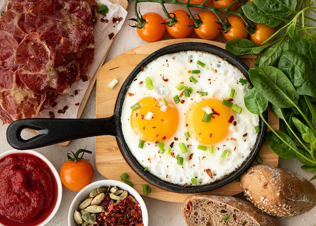 Two fried eggs with herbs and spices in a small skillet