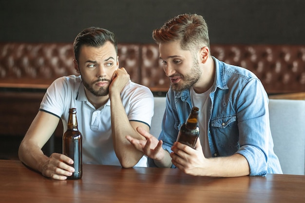 Two friends drinking beer in cafe together