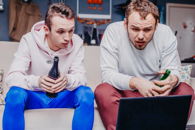 Two friends fans with beer watching football