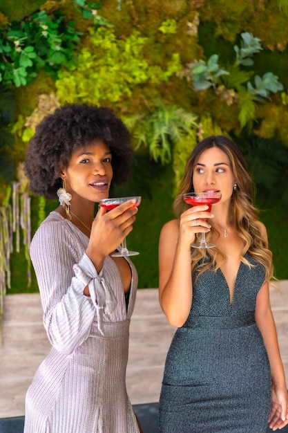 Two friends in gala dresses having a cocktail at a party in a hotel, lifestyle. Glamor lifestyle, exclusive party