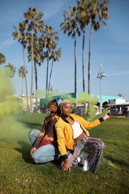 Photo two friends having fun in the park and playing with a smoke bomb