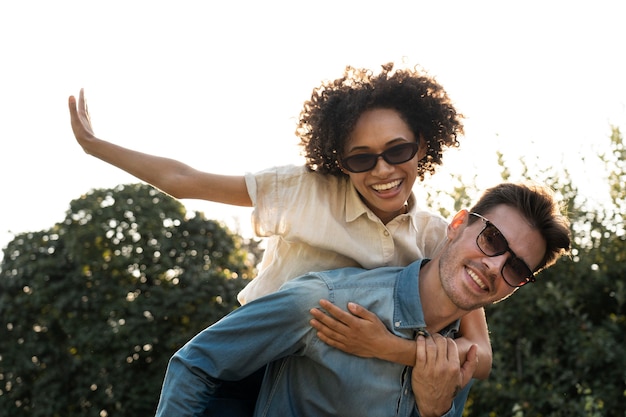 Photo two friends having fun together outdoors while piggyback riding