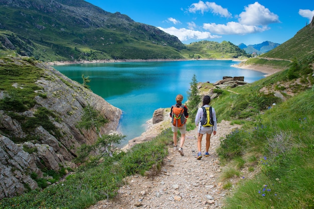 Two friends during a hike in the mountains walking near an alpin