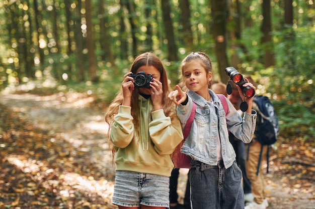 Two friends kids in green forest at summer daytime together