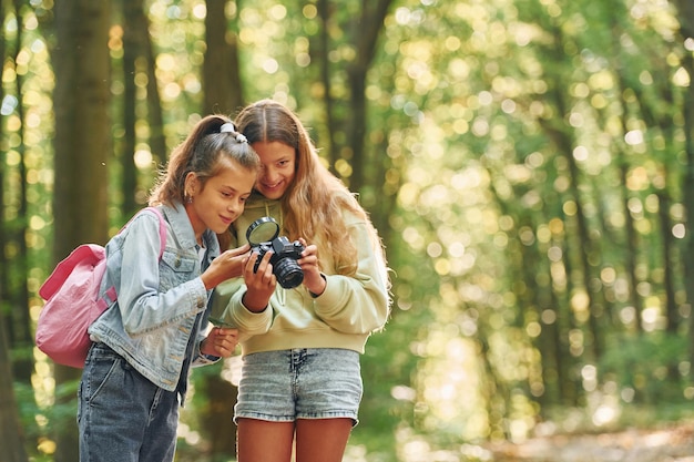 Photo two friends kids in green forest at summer daytime together