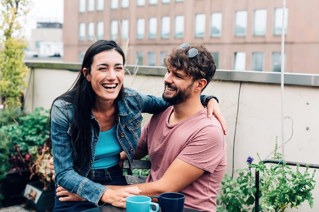 Photo two friends laughing girl sitting on the boy's legs hugging him