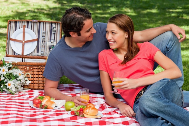 Two friends looking at each other while lying on a blanket with a picnic