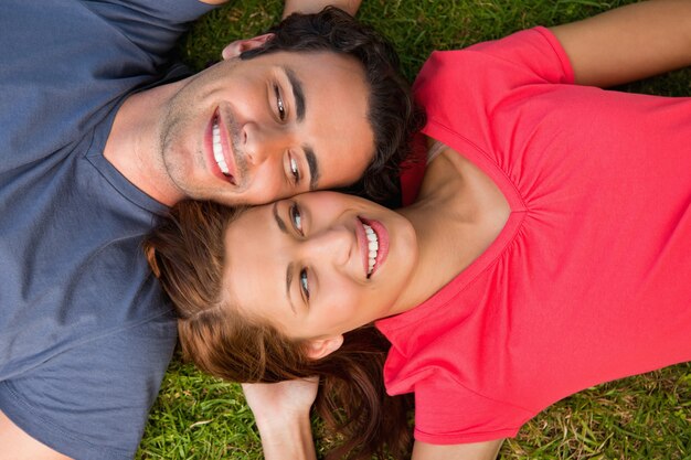 Two friends looking at each other while lying head to shoulder