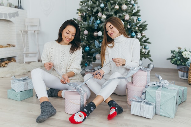 Two friends open Christmas gifts.