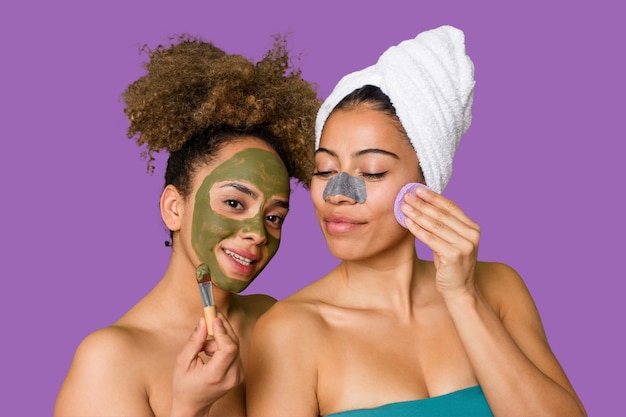Two friends pamper themselves with facial treatments for a relaxing spa day at home with laughter and enjoyment nourishing their skin for a glowing confident look
