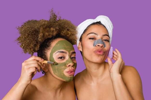 Two friends pamper themselves with facial treatments for a relaxing spa day at home with laughter and enjoyment nourishing their skin for a glowing confident look