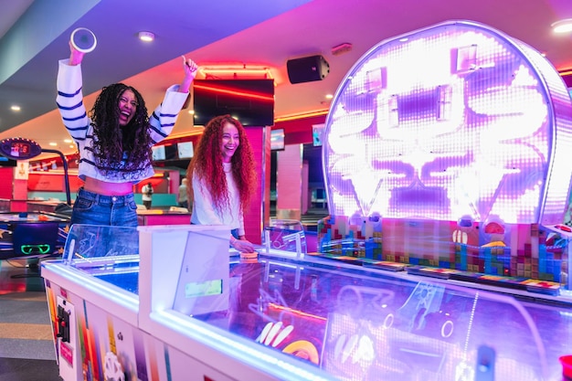 two friends playing air hockey celebrating victory in bowling alley arcade