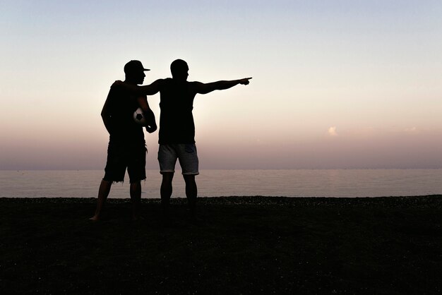 Due amici che si rilassano dopo aver giocato a calcio in spiaggia.