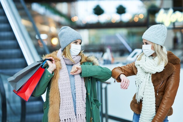 2人の友人がマスク、コロナウイルスの概念を身に着けて一緒に買い物