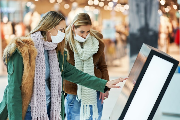 Photo two friends shopping together wearing a mask, coronavirus concept