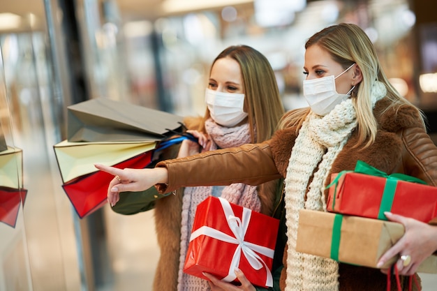 two friends shopping together wearing a mask, coronavirus concept