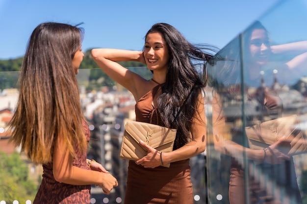 Two friends smiling on summer vacations in a viewpoint of the city