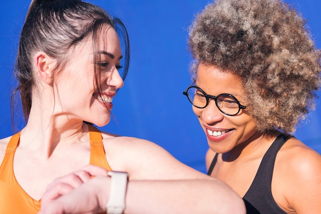 Two friends using a smart watch practicing sports